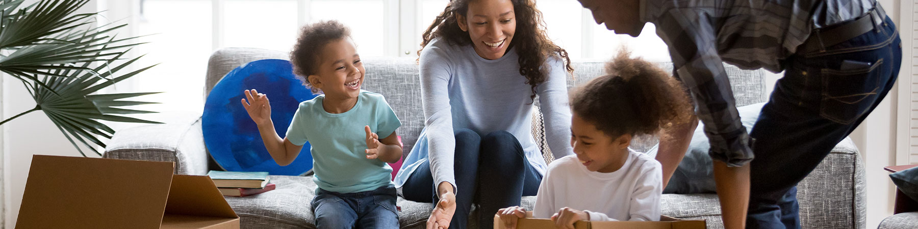 family playing with boxes in living room of new home