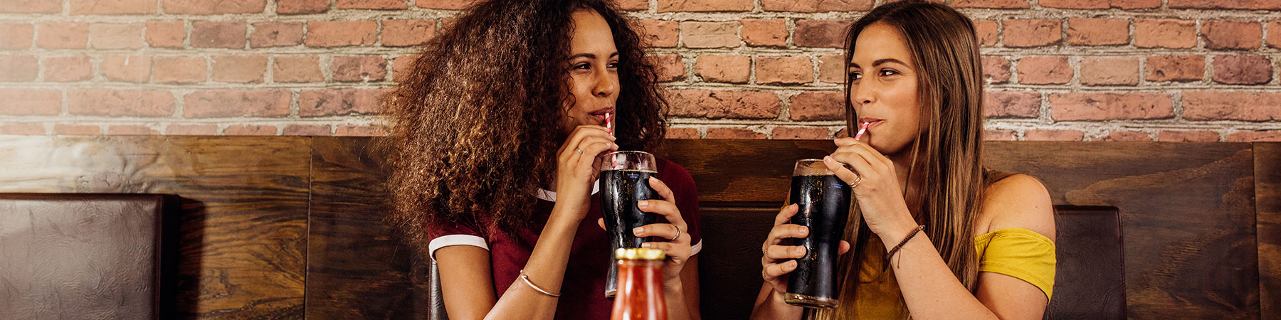 Best friends enjoying drinking cola at cafe