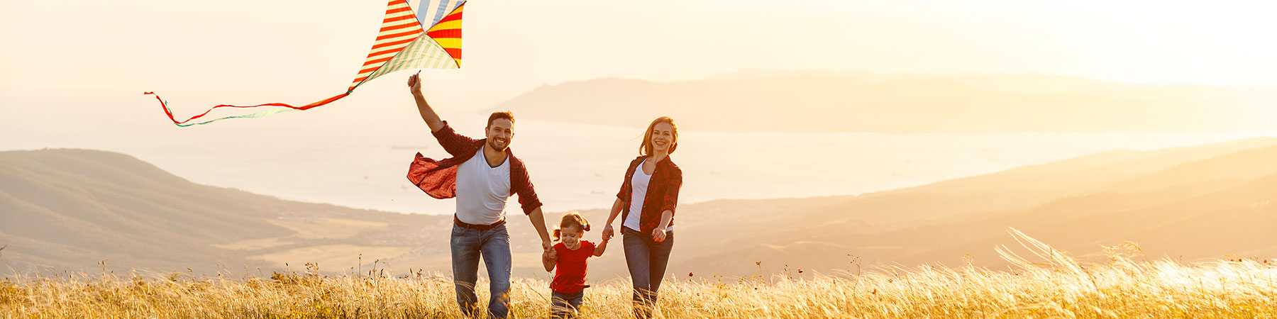 Happy family father, mother and child daughter launch a kite on nature at sunset